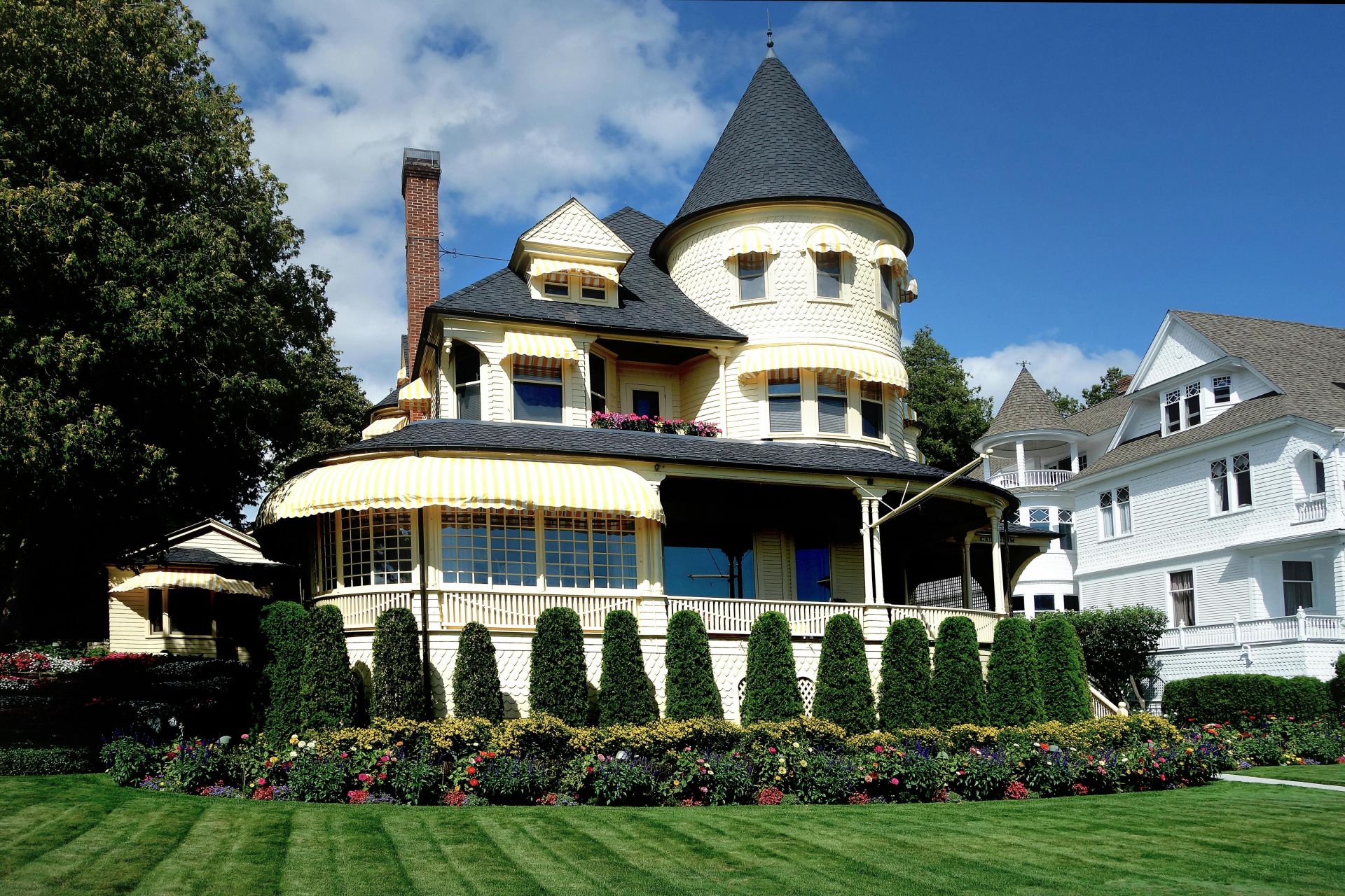 Beautiful Victorian-style house with lush garden and blue skies in Michigan, USA.